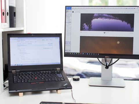 Laptop mit PHP-Code auf GitHub neben einem großen Monitor auf hellem Schreibtisch