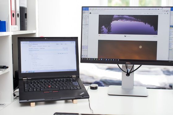 Laptop mit PHP-Code auf GitHub neben einem großen Monitor auf hellem Schreibtisch