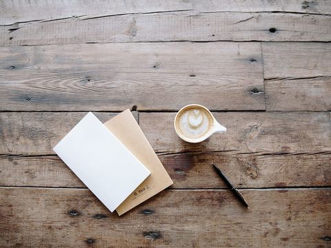 Zwei Notizhefte, Kugelschreiber und Cappuccino auf einem rustikalen Holztisch von oben