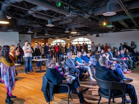 Publikum bei einem Startup-Pitch-Abend in einem Loft mit Industriedecke und Holzboden