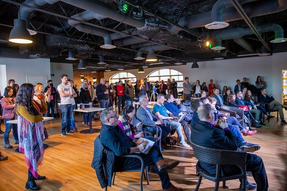 Publikum bei einem Startup-Pitch-Abend in einem Loft mit Industriedecke und Holzboden